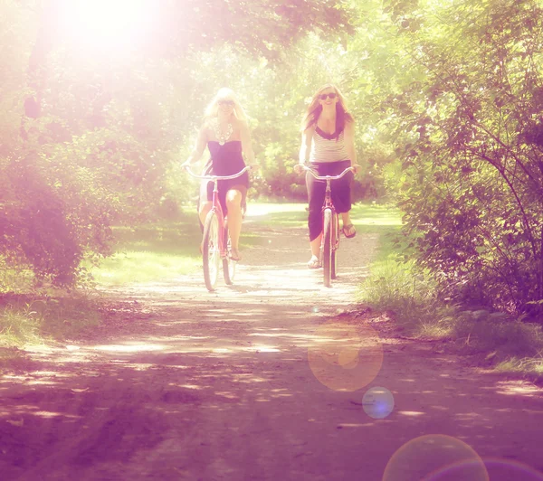 Two girls riding bikes in a park — Stock Photo, Image