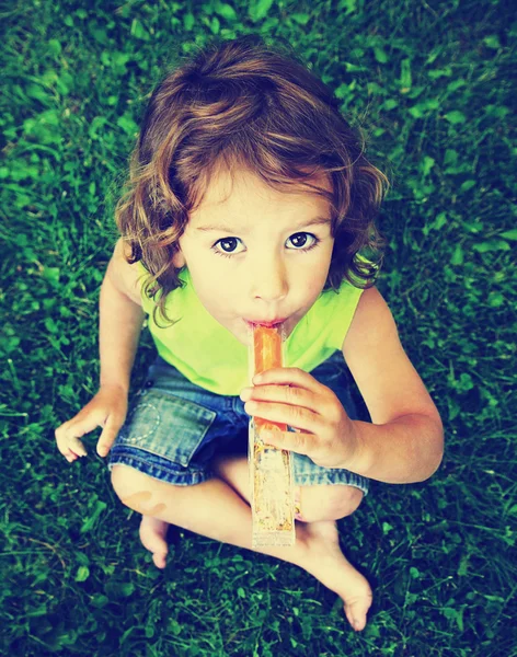 Girl eating frozen treat in grass