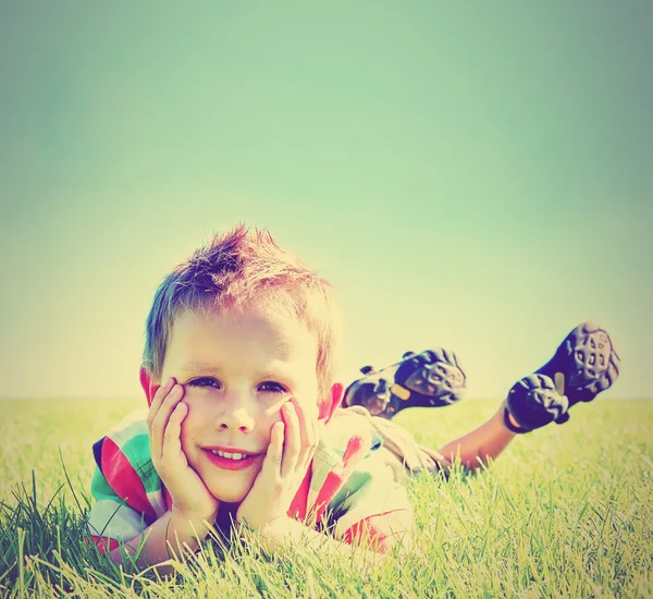 Jongen in het gras te leggen — Stockfoto