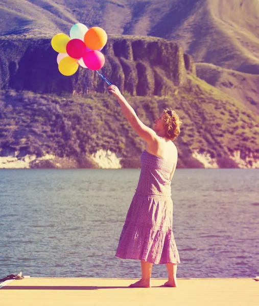 Woman on dock with balloons — Stock Photo, Image