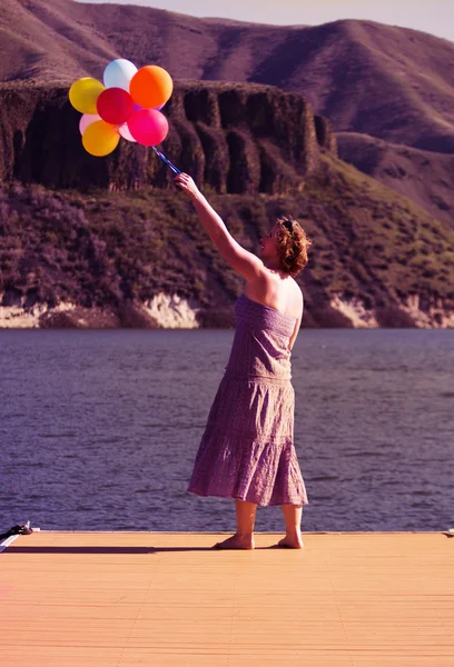 Woman on dock with balloons — Stock Photo, Image