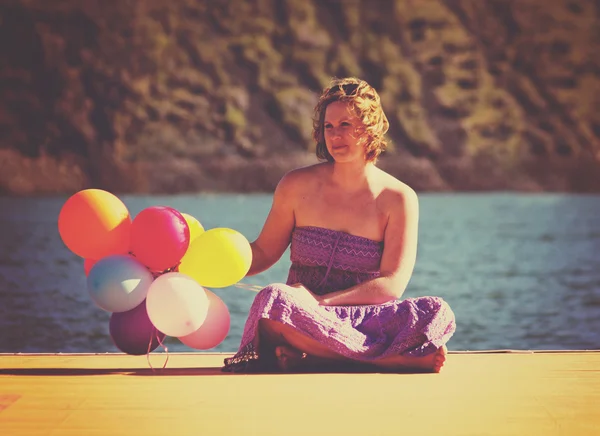 Woman on dock with balloons — Stock Photo, Image