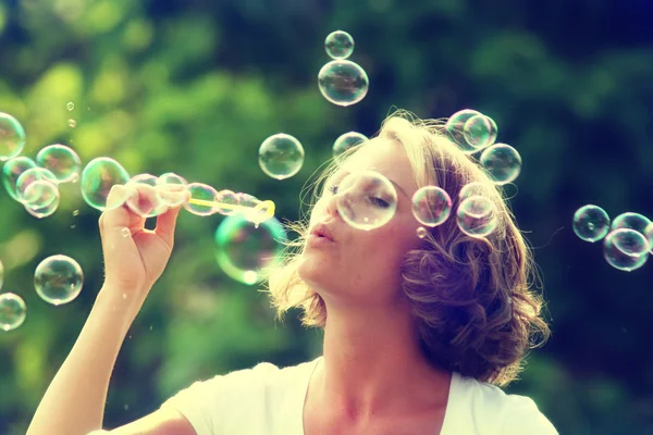Beautiful woman blowing bubbles — Stock Photo, Image