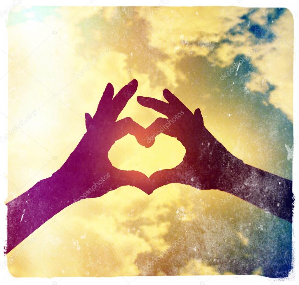 Two hands making heart shape in sky