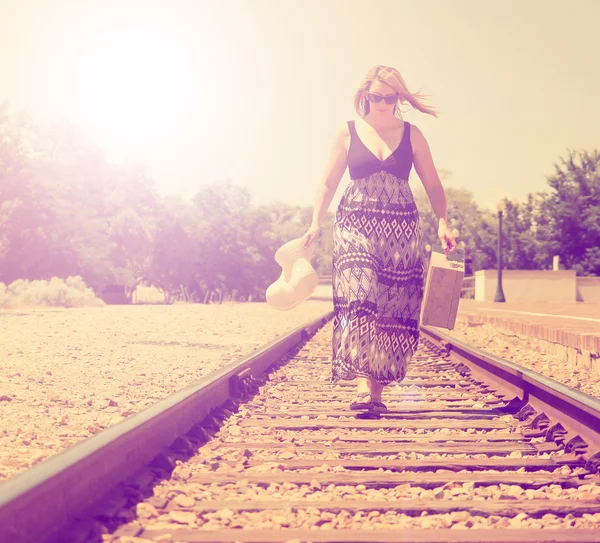Tyttö kävelee pitkin junaraiteita — kuvapankkivalokuva