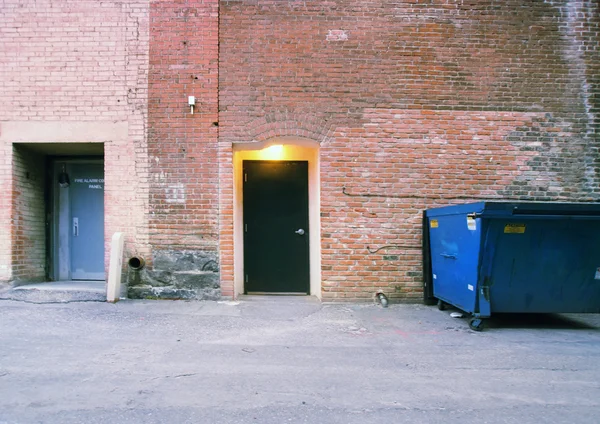 Poubelle contre un vieux mur de briques — Photo