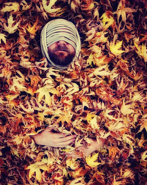 Man with rope around head in leaves — Stock Photo, Image