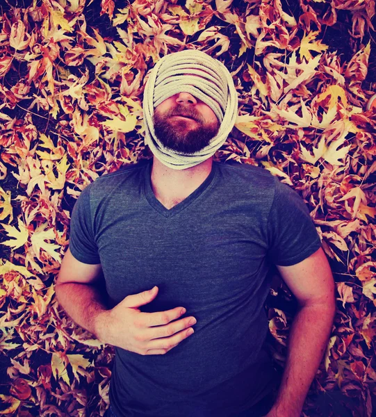 Homem com corda ao redor da cabeça nas folhas — Fotografia de Stock