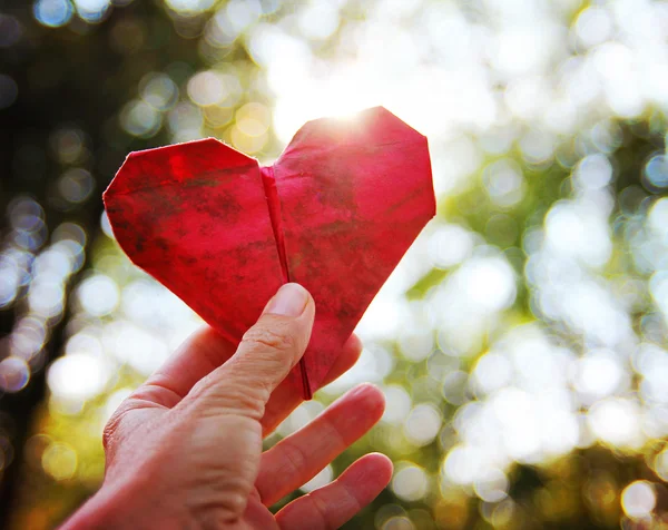 Hand met origami papier hart — Stockfoto