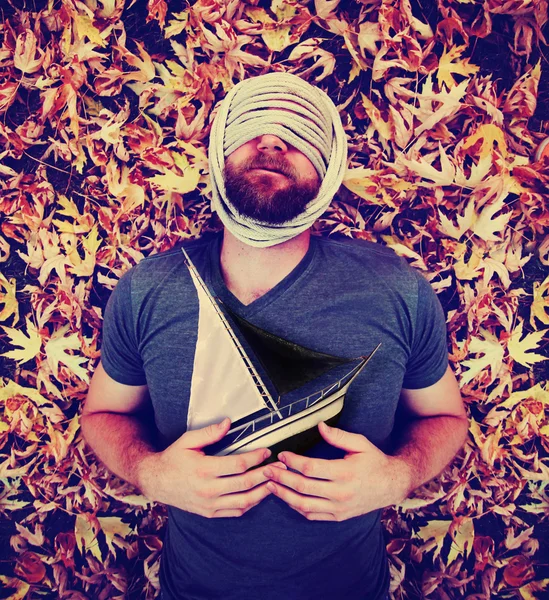Hombre en hojas sosteniendo velero —  Fotos de Stock