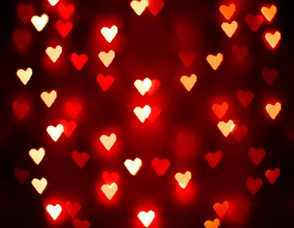 Un fondo agradable con luces desenfocadas borrosas en la forma de corazones buenos para las vacaciones como el día de San Valentín o los anuncios de boda o tarjetas románticas — Foto de Stock