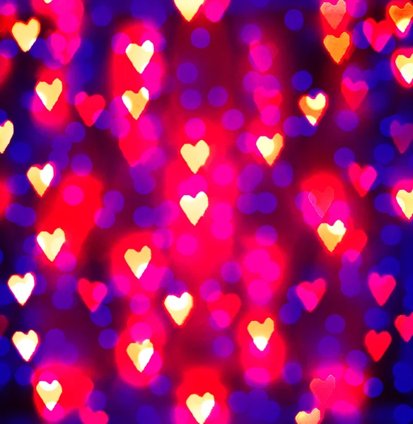 Un fondo agradable con luces desenfocadas borrosas en la forma de corazones buenos para las vacaciones como el día de San Valentín o los anuncios de boda o tarjetas románticas — Foto de Stock