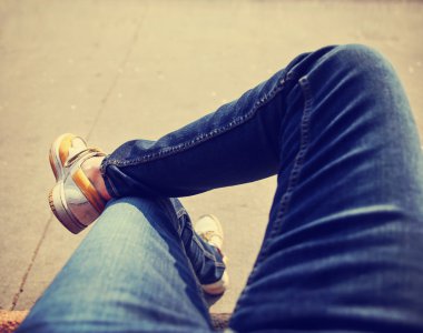 Şehir merkezinde çapraz ayaklı bir kaldırım bankta oturan bir hipster