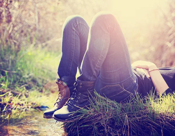 Девушка лежит на маленьком острове в ручье в джинсах и черном — стоковое фото
