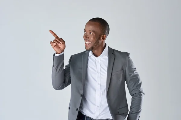 Smiling businessman pointing in studio — Stock Photo, Image