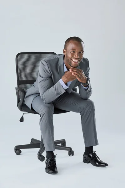 Glada leende affärsman som sitter i stol — Stockfoto