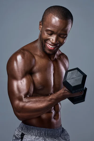 Здоровый улыбающийся черный мужчина, несущий тяжести в студии — стоковое фото
