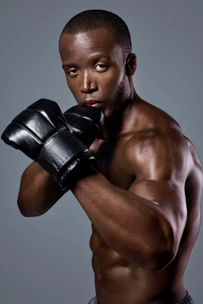 Gespierde magere man bokser in zwarte boxing bokszak handschoenen — Stockfoto