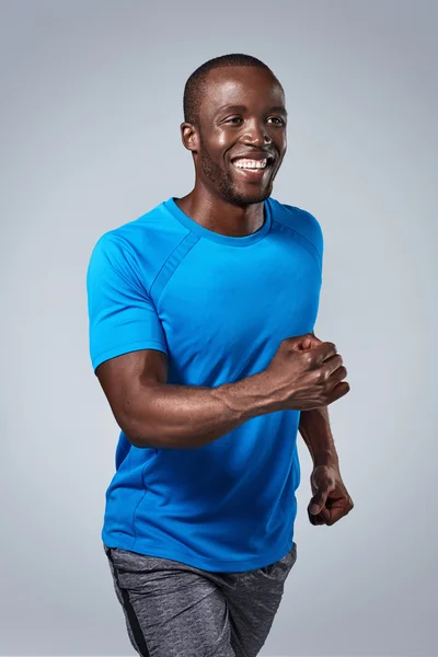 Smiling portrait of black african man running in studio — Stock Photo, Image