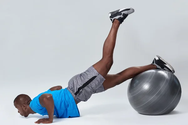 Člověk dělá noha výtahem zpět cvičením v posilovně fitness míč — Stock fotografie