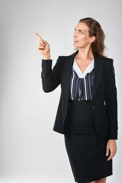 Businesswoman pointing and looking to the side — Stock Photo, Image