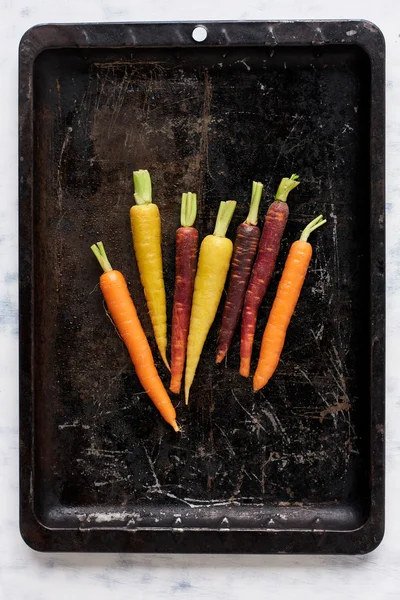 Colourful carrots on old baking pan — Stock Photo, Image