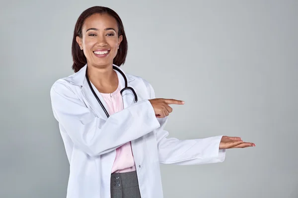 Female doctor in lab coat and sethoscope pointing — Stock Photo, Image