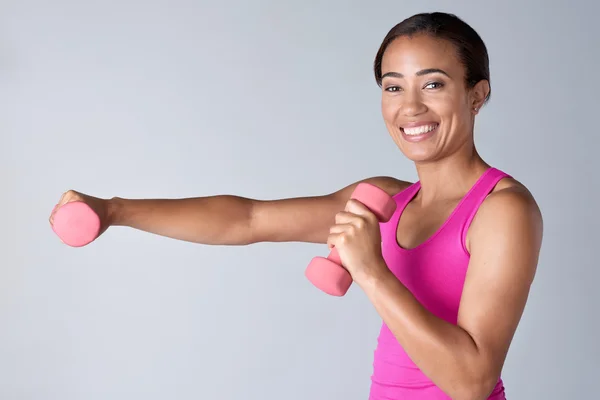 Happy woman exercising with dumbbells in studio — Stock Photo, Image