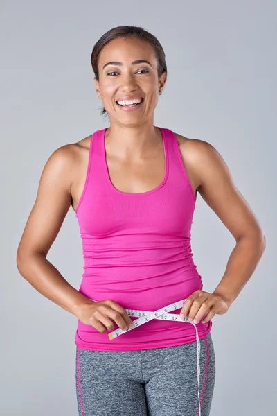 Fit woman holding measuring tape against waistline — Stock Photo, Image