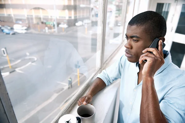 Afrikaanse zakenman met koffie en telefoon — Stockfoto
