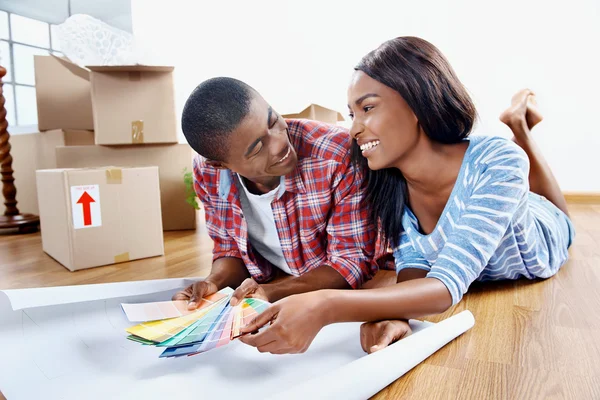 Pareja africana decidiendo sobre el color de la pintura — Foto de Stock