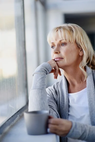 Frau schaut aus dem Fenster — Stockfoto