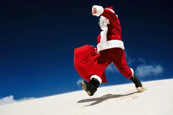 Noel Baba kumsalda yürürken — Stok fotoğraf