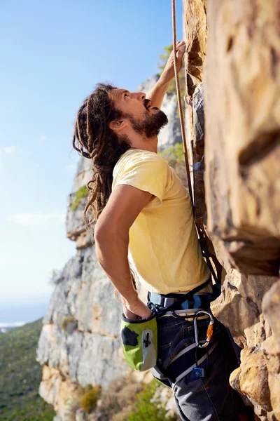 Man climbing up steep mountain — Stock Photo, Image