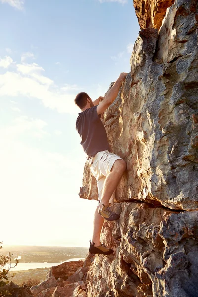 Rock climber climbing up steep of mountain Stock Image