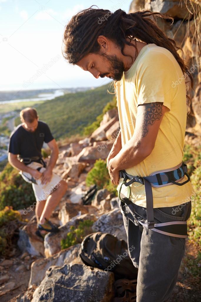 Two men putting on climbing equipment