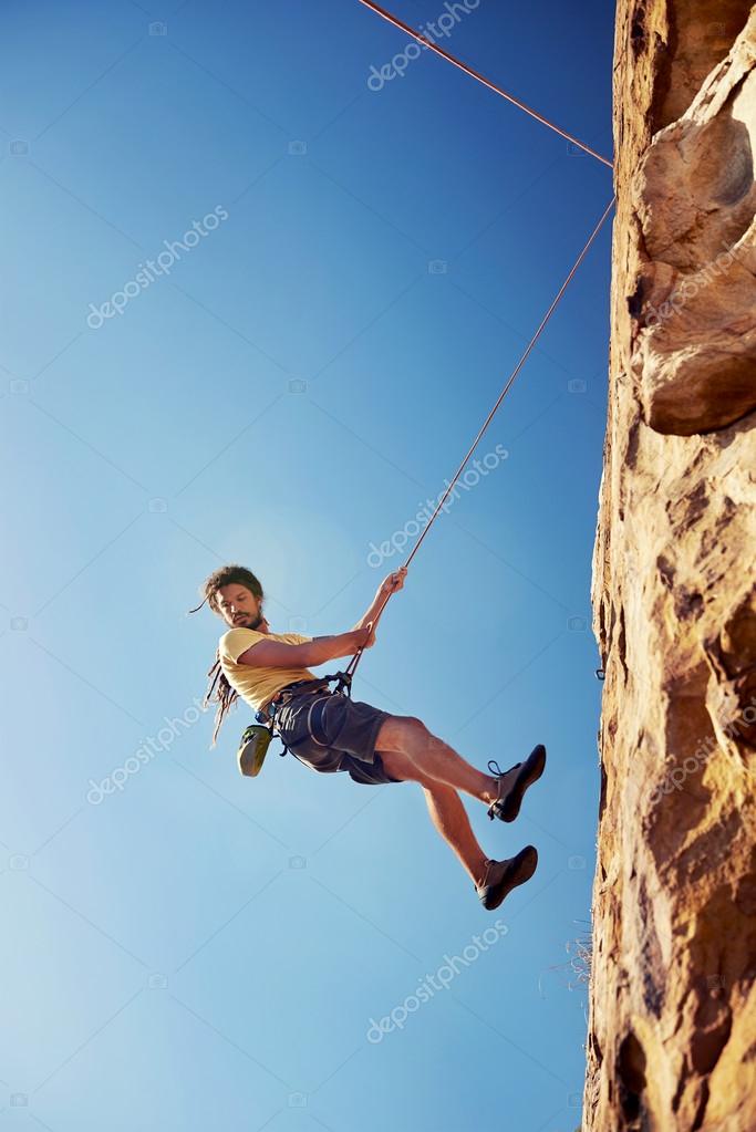 Man rappelling down mountain Stock Photo by ©Daxiao_Productions 74907571