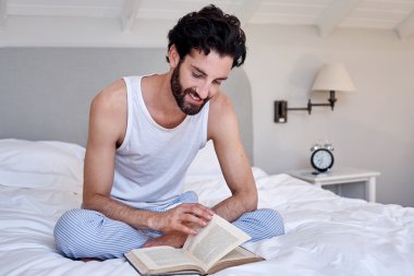 adam yatakta kitap okuma