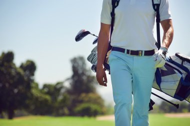 Golf player walking and carrying bag clipart