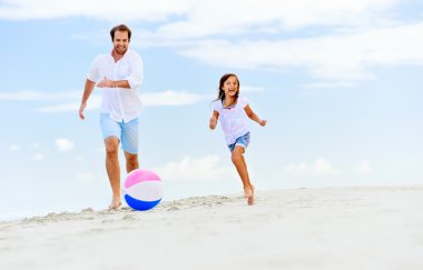 Baba ve kızı sahilde koşuyor.