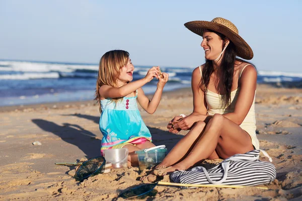 Mother and daughter looking at shell collection — Stock Photo, Image