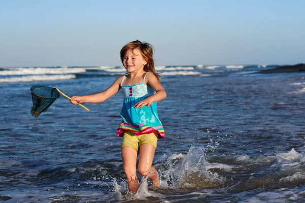 Young girl on beach with fishing net — Stock Photo, Image