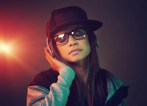 Mujer de moda escuchando música en los auriculares — Foto de Stock