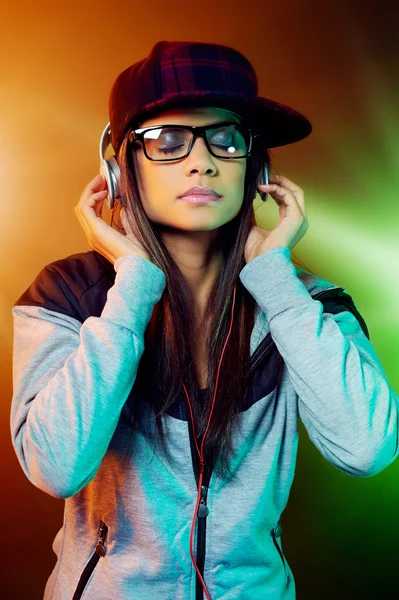 Mujer de moda escuchando música en los auriculares — Foto de Stock