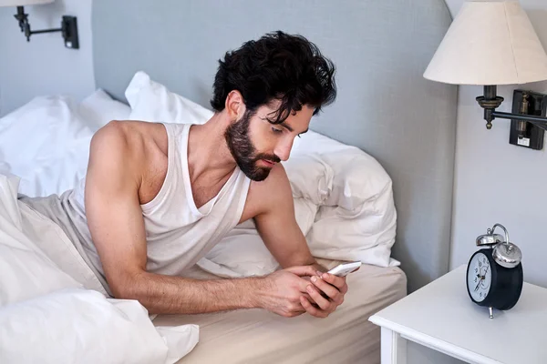 Homme avec téléphone portable couché au lit — Photo