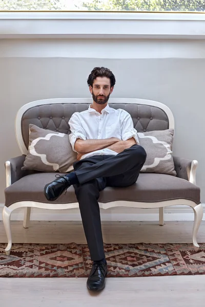 一个英俊的男人坐在家里的沙发上 — 图库照片