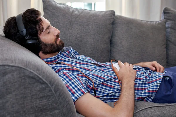 Homem ouvindo música no sofá — Fotografia de Stock