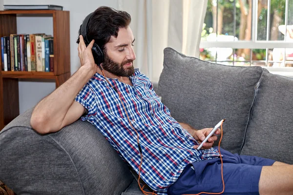 Homem ouvindo música no sofá — Fotografia de Stock