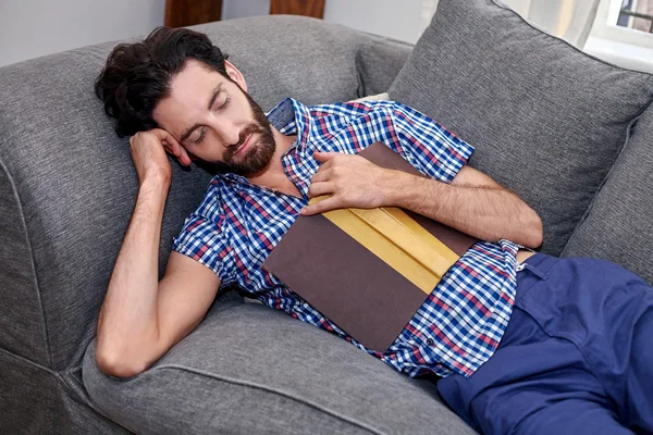 Uomo che dorme sul divano durante la lettura del libro — Foto Stock