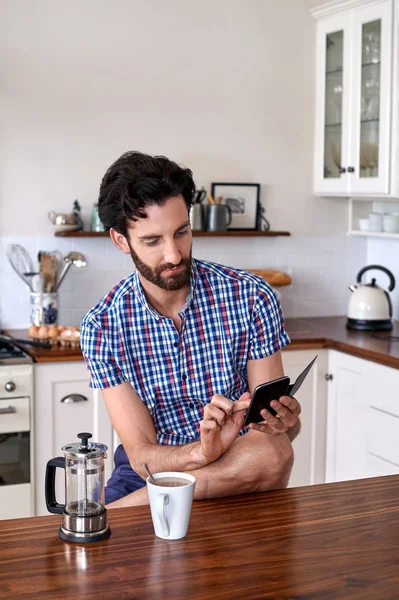 Muž si kávu s mobil doma — Stock fotografie